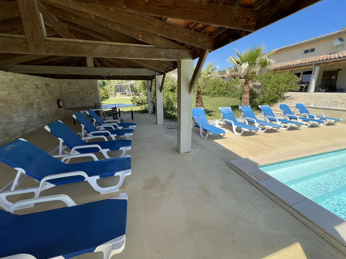 Sonnenliegen unter der überdachten Terrasse am Pool